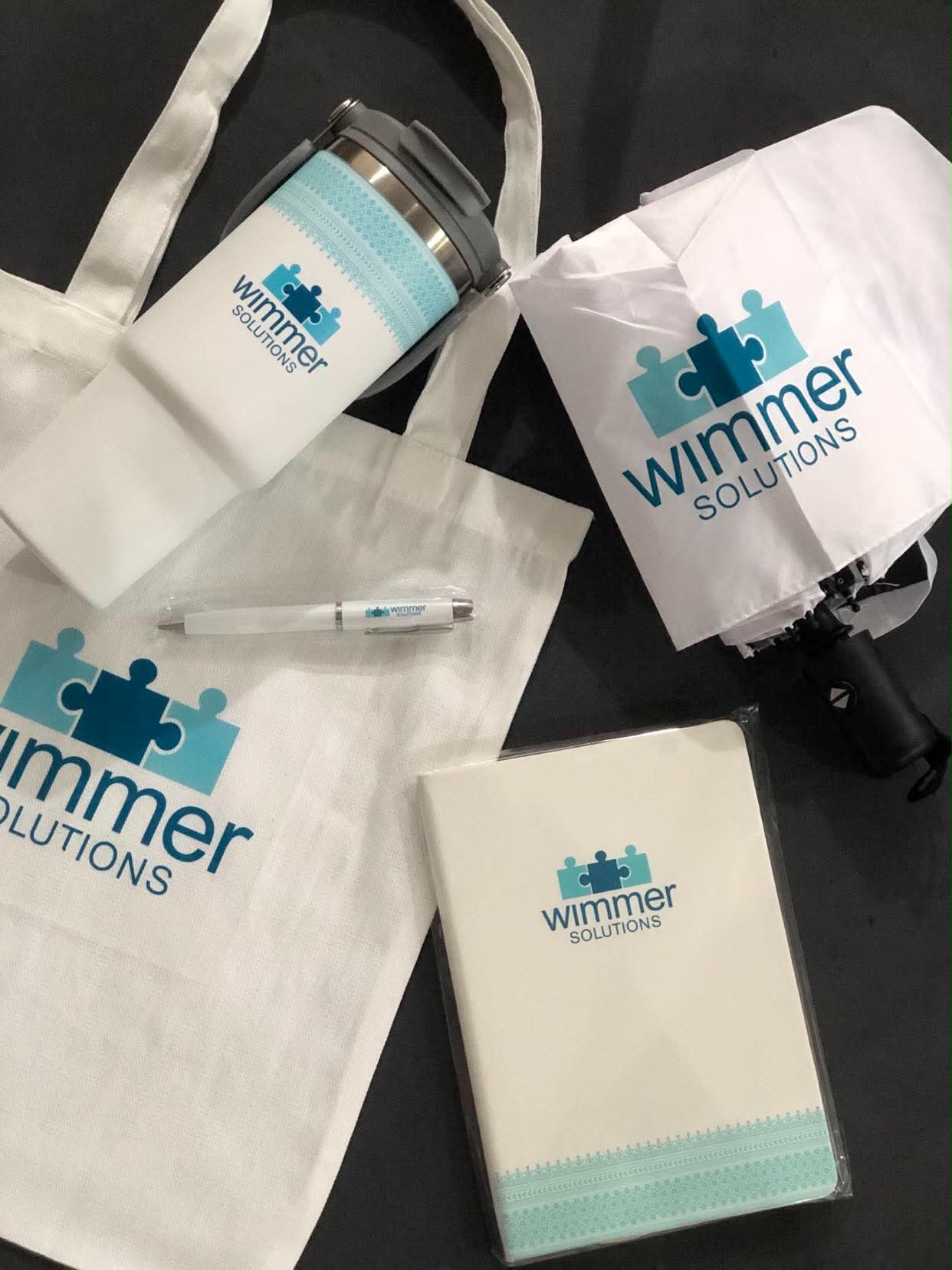 Wimmer Solutions gift bundle with a printed tumbler, tote bag, umbrella, pen and notebook